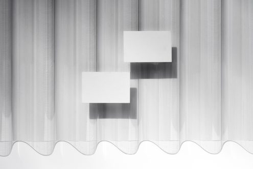Blank white business cards floating against sheer curtain with soft shadows