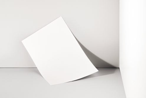 Clean white tilted blank card on minimal beige wall with soft shadow
