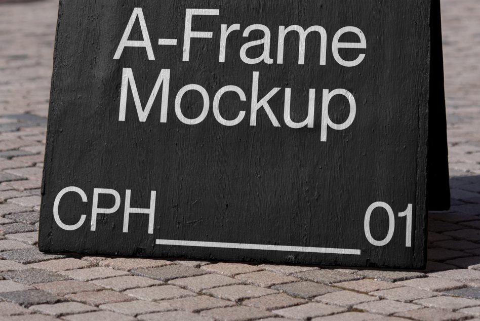 Close-up of black wooden A-Frame sign with white lettering on pavement