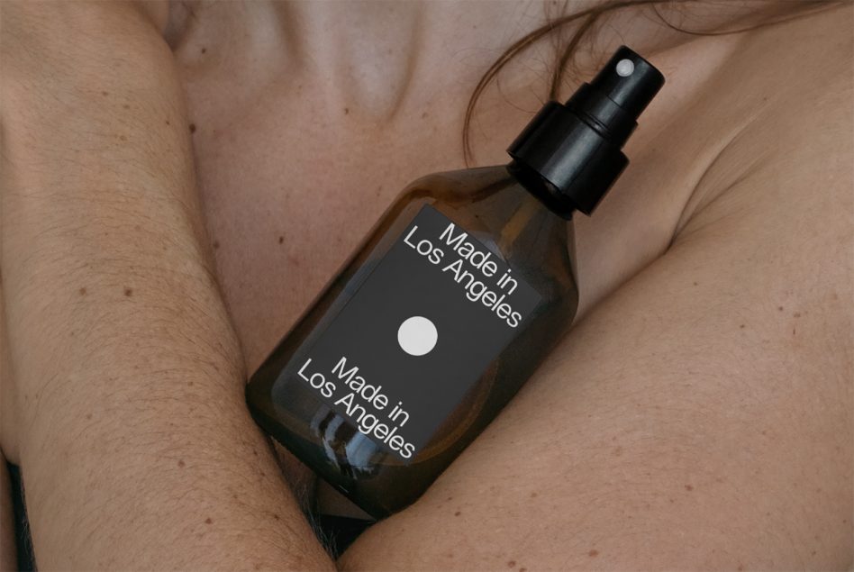 Cosmetic spray bottle mockup held by a person, showcasing label design with "Made in Los Angeles" text, for beauty product branding.