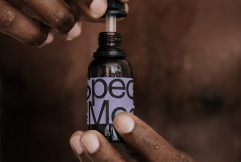 Close-up of hands holding a dropper bottle with a modern label design, ideal for product mockup graphics.