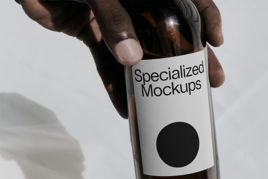 Person holding a bottle with label reading Specialized Mockups, ideal for product presentation, branding, and packaging design.