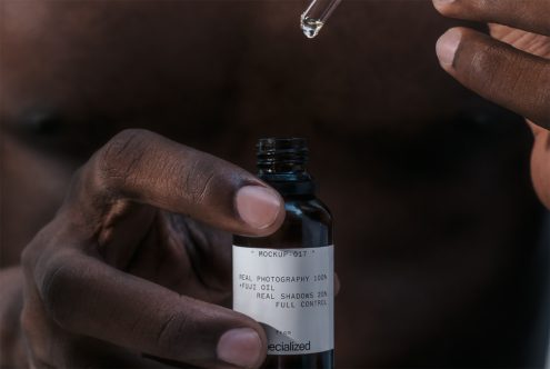 Close-up product mockup featuring a person holding a dropper bottle with a customizable label, ideal for branding and packaging design.