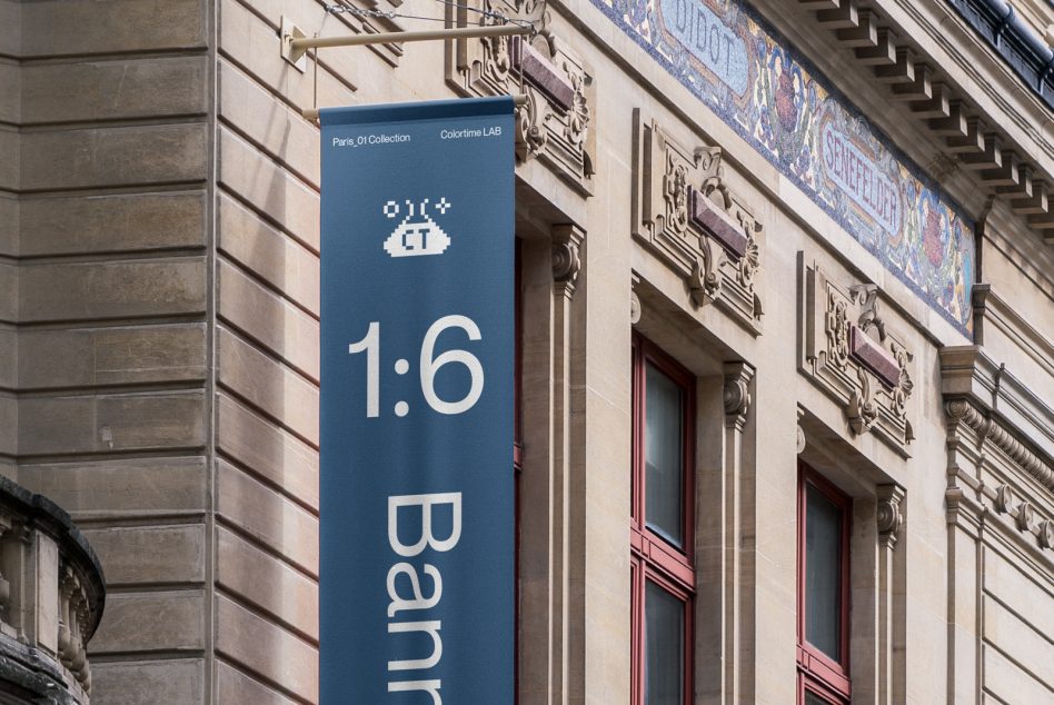 Vertical teal banner with white text mounted on classical building exterior with ornaments