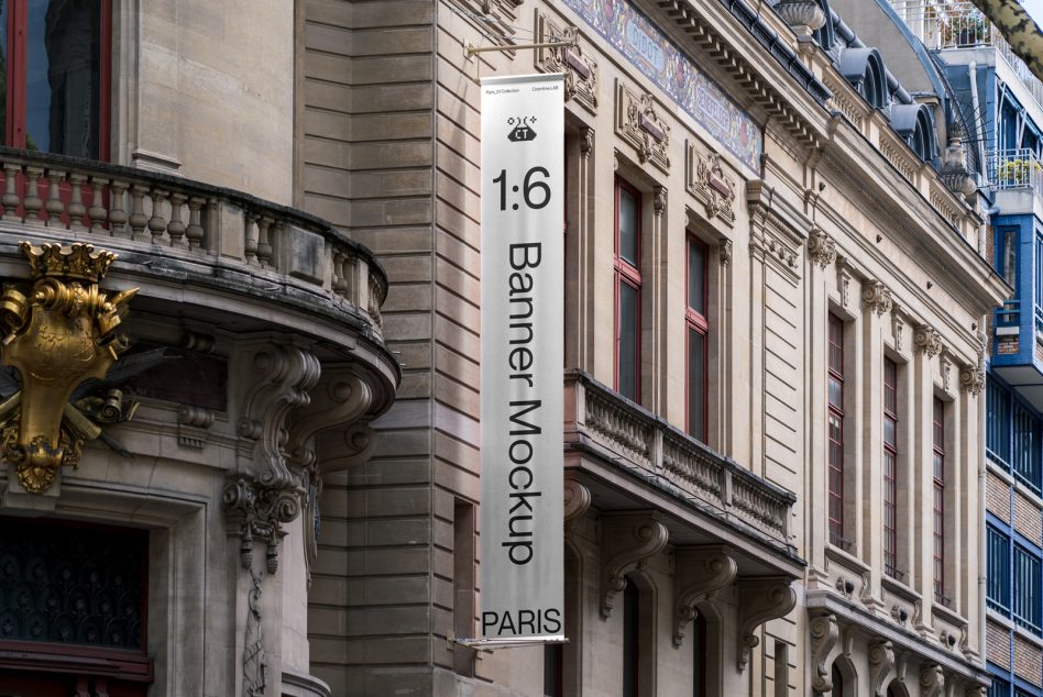 White banner with black text hanging on stone building between ornamental architectural details