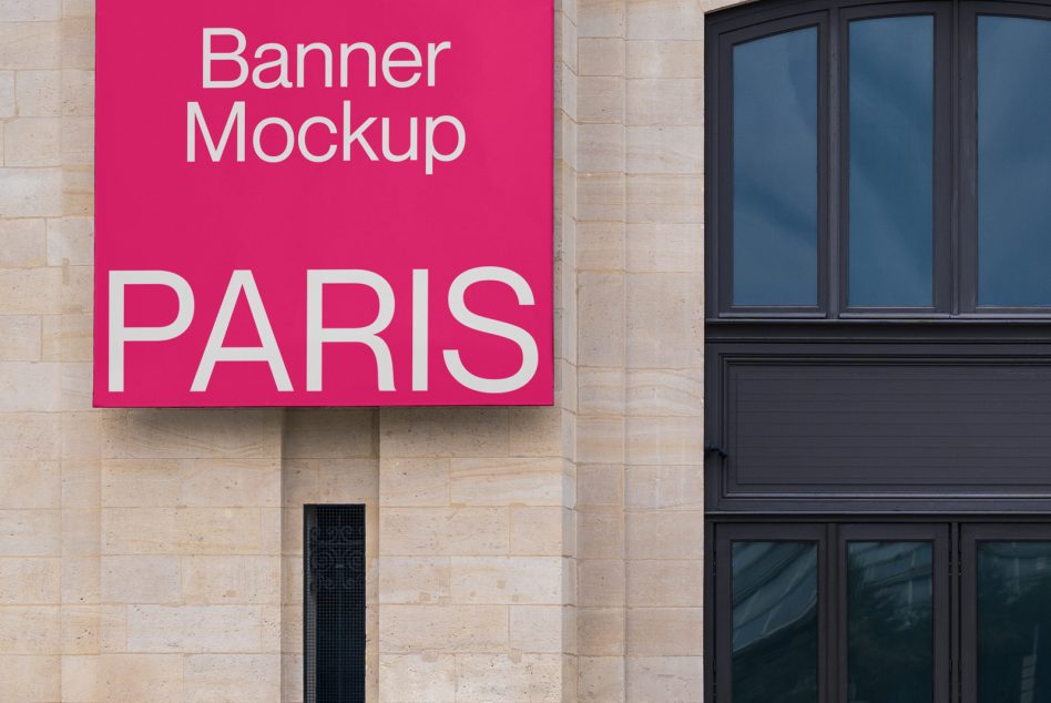 Bright pink square banner with white text mounted on beige stone building facade