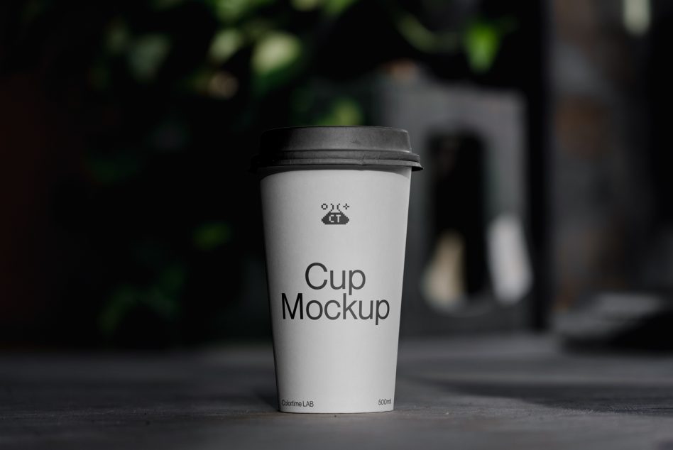 White takeout coffee cup with black lid sitting on pavement outdoors