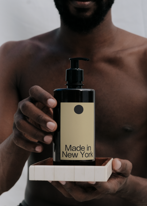Minimalist body lotion bottle with Made in New York label on cream display block