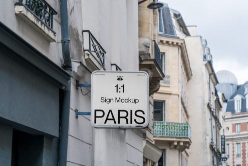 Square white sign mounted on Paris building facade showing PARIS text