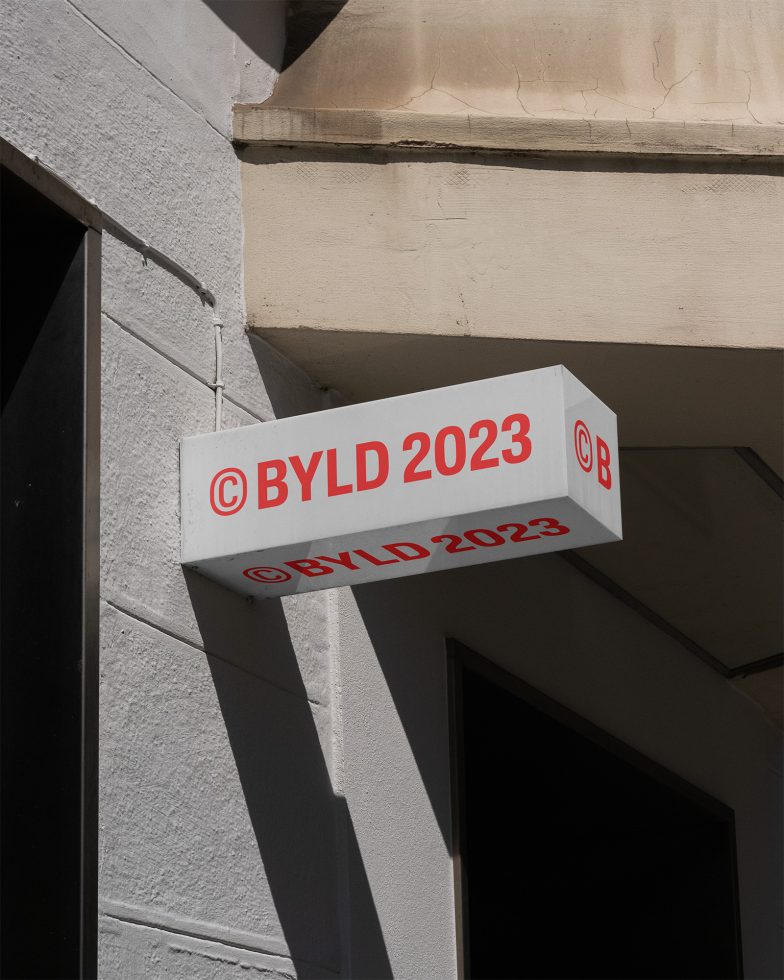 Outdoor signage mockup on building facade with red text BYLD 2023, realistic urban setting for branding presentation.