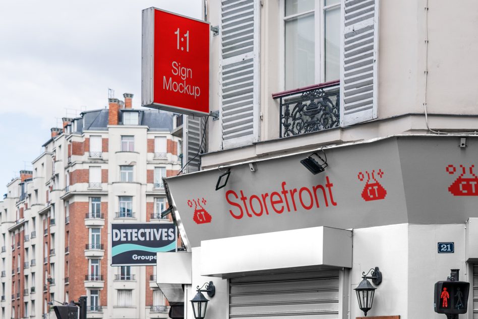 Red square sign mounted above Parisian storefront with awning signage