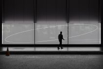 Runner passing large illuminated storefront with curved white lines