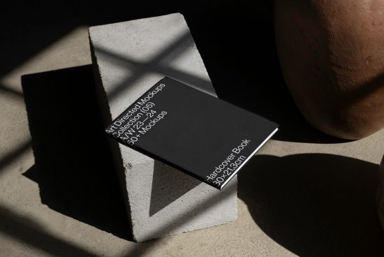 Black hardcover book mockup on concrete block with shadow play, realistic photo presentation, designer assets, graphic design mockups.