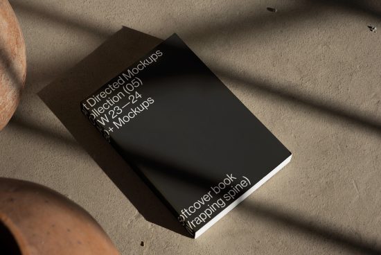 Realistic book mockup on textured surface with shadows, ideal for digital asset marketplace, perfect for designers to showcase work.