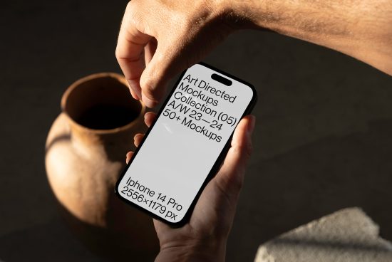 Hand holding smartphone mockup with editable screen, modern iPhone model, digital asset for app design presentation, isolated on a textured background.