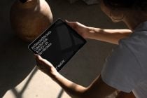 Hands holding iPad Air in landscape showing black screen display in bright sunlight