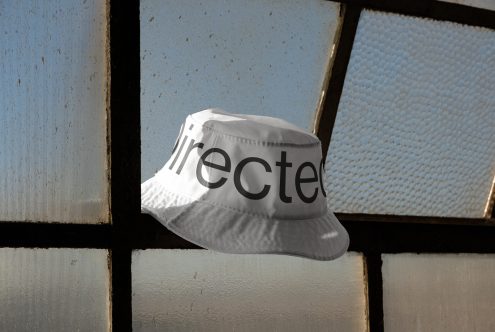 White bucket hat with a logo mockup placed against an industrial window, natural lighting, ideal for branding presentations.