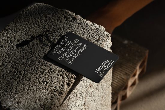 Black hangtag mockup on textured surface with dramatic lighting, perfect for branding presentations in the Mockups category for designers.