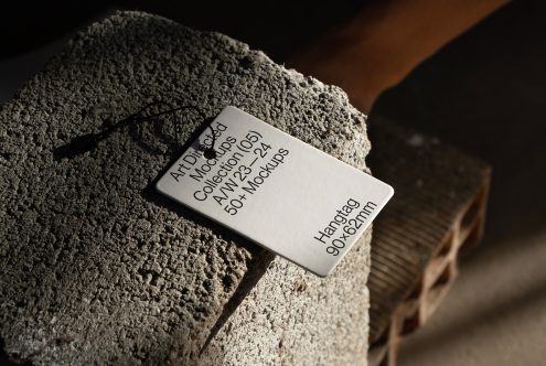 White hangtag mockup with black string on textured concrete surface, natural lighting, suitable for branding presentations, dimensions visible.