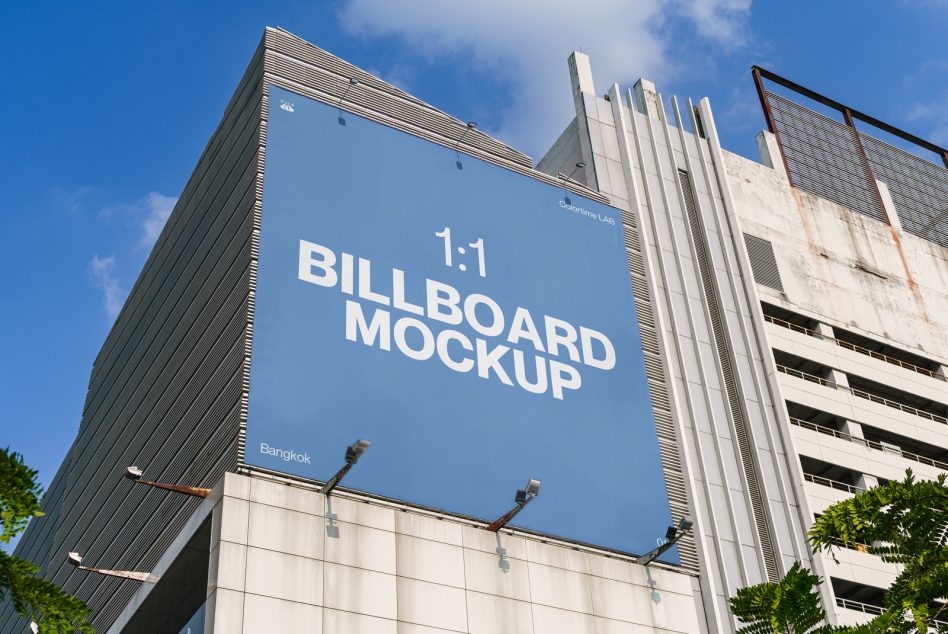 Blue sky behind large square billboard mockup mounted on contemporary building facade with text layout