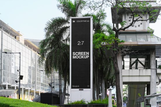 Outdoor digital billboard screen mockup in urban setting with tropical foliage, ideal for designers to display ads and branding graphics.