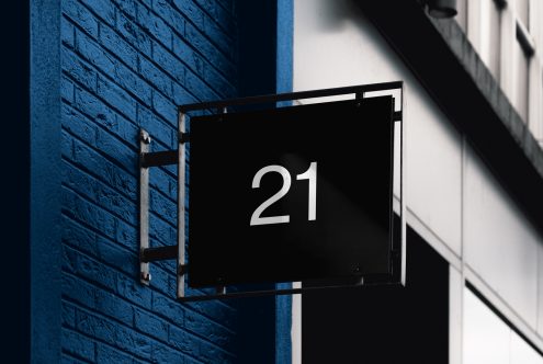 Elegant black signboard with white numerals mockup on a blue brick wall, ideal for designers creating branding or signage presentations.