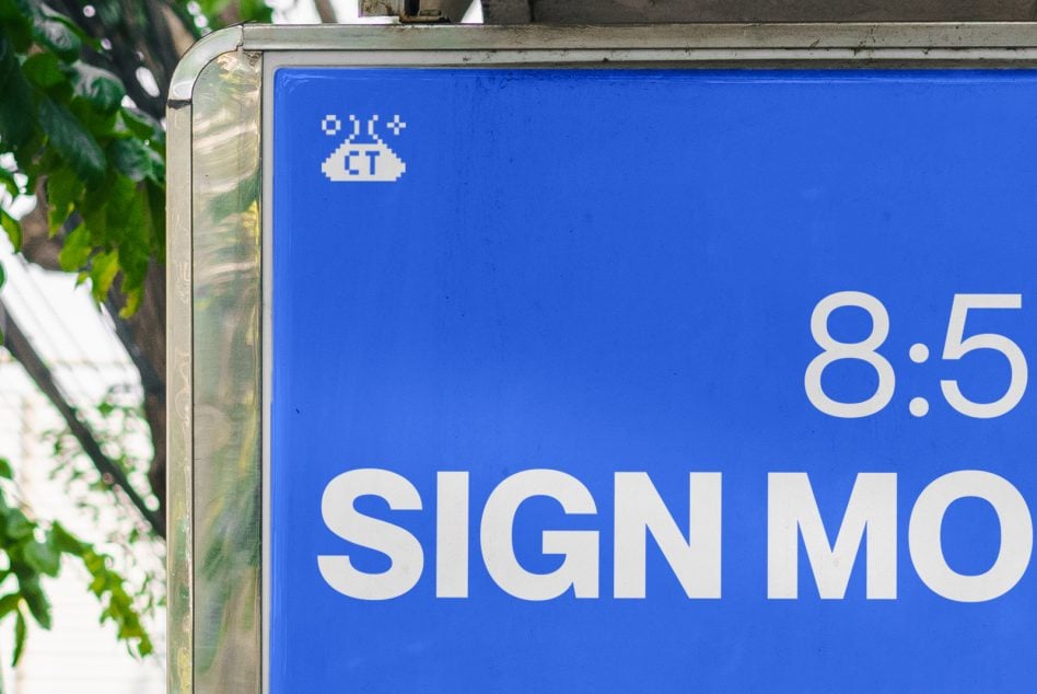 Bright blue street sign with white text showing 8.5 ratio, shot outdoors with green foliage