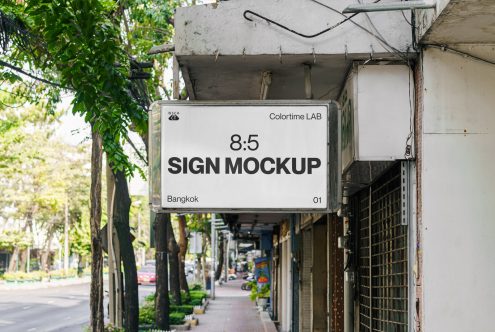 Outdoor sign mockup hanging on a building in an urban street setting, perfect for showcasing billboard designs and branding to designers.