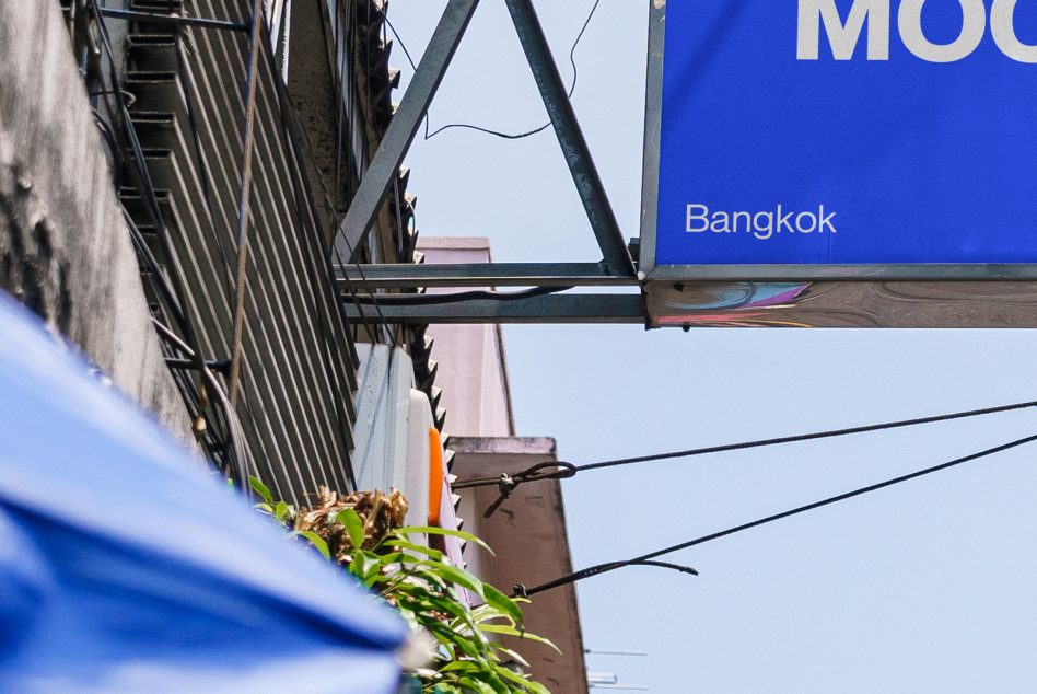 Urban street sign mockup showcasing 'Bangkok' nameplate for city branding and design presentations, surrounded by architectural details.