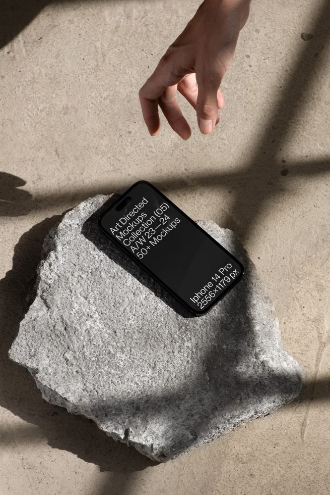 Smartphone screen mockup on a stone, hand reaching out, natural light shadow play, ideal for displaying UI/UX designs, realistic textures, digital asset.