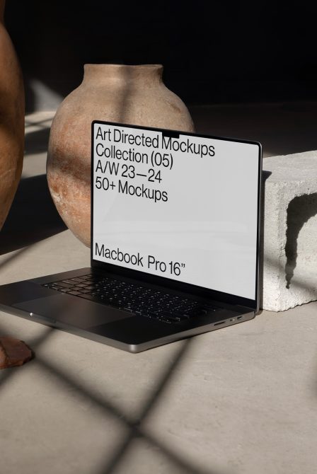 Laptop mockup for designers featuring a MacBook Pro 16 inch on a textured surface near a terracotta vase, digital assets, realistic shadows.