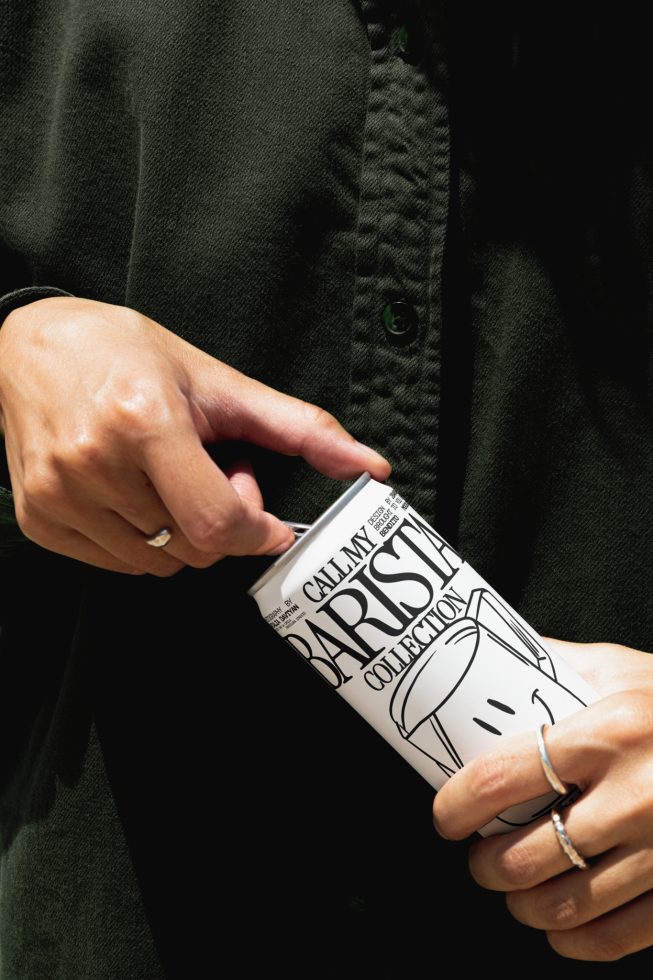 Person holding a coffee cup with a stylish design, ideal for mockup graphics showcasing branding and packaging designs.