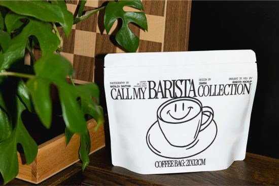 Packaging mockup of a coffee bag with a smiling cup design, standing on wood next to a plant, showcasing product design for branding.