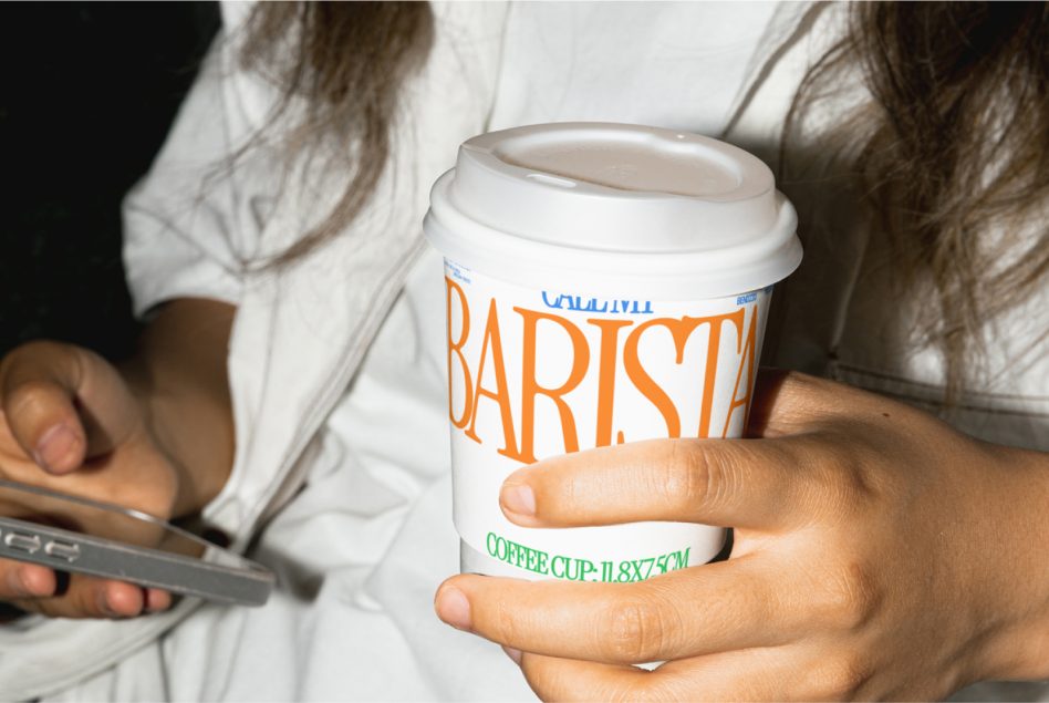 Person holding a branded coffee cup mockup, ideal for display of label designs in a realistic setting. Great for graphic design assets.