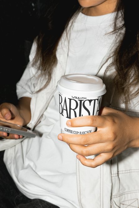 Person holding a coffee cup mockup with phone, showcasing branding potential for designers, ideal for mockups category in digital asset marketplace.