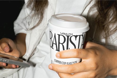 Close-up of a person holding a branded paper cup mockup, ideal for designers to showcase coffee shop logo designs.