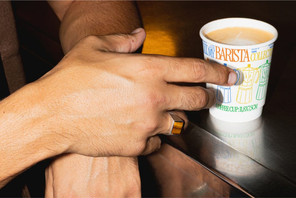 Person holding a coffee cup mockup with barista design on a sleek surface. Ideal for branding, packaging designs, and product presentation.