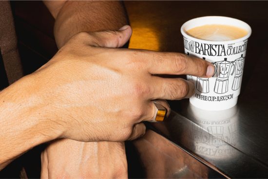 Person holding a paper coffee cup with a design mockup on a reflective surface, ideal for showcasing packaging and branding design.