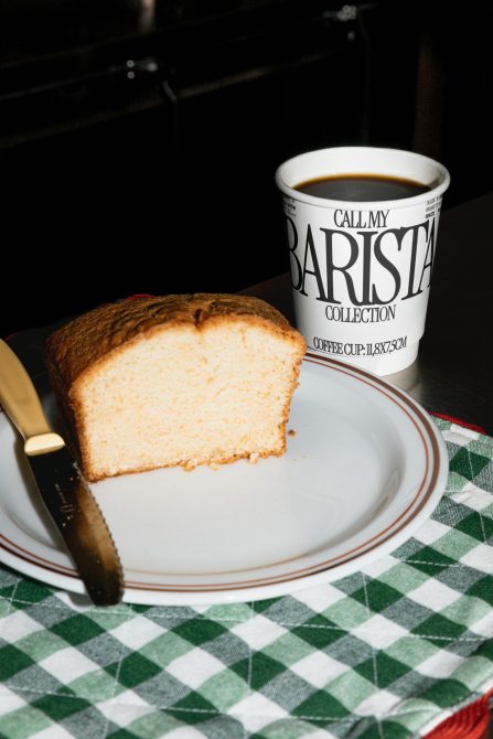 Sliced cake on plate with coffee cup, knife, green checkered napkin, for mockup or graphic design elements in cafe setting.