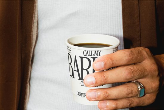 Person holding a coffee cup with typography design, ideal for mockup graphic assets, showcasing brand identity design in a realistic setting.