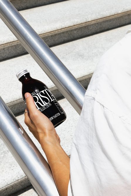 Person holding a branded bottle mockup with modern typography, showcasing label design for urban product presentation, suitable for mockups category.