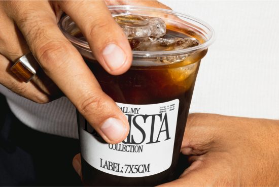 Close-up image of a hand holding an iced coffee cup with a customizable label design for mockup, showcasing the label mockup on the cup.
