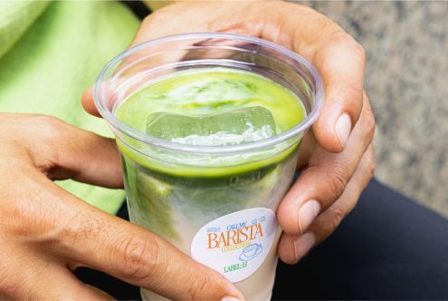 Close-up of hands holding a cup with a layered green tea latte mockup, ideal for graphics, beverage presentation, and branding designs.