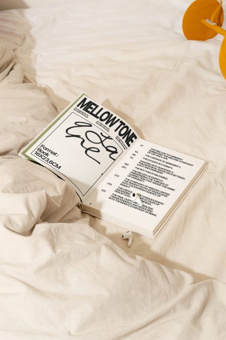 Open book mockup on a crumpled bedsheet with AirPods, showcasing modern font design, perfect for Templates, Graphics, or Presentation displays.