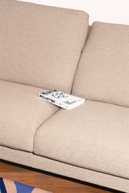 Neutral fabric sofa with a graphic design magazine on it, interior design mockup for showcasing print layouts for designers.