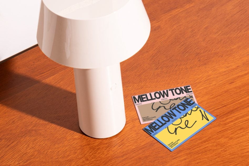 White lamp next to colorful Mellow Tone business cards on warm wood floor