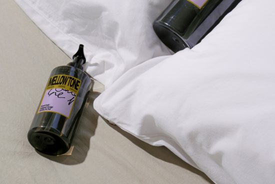 Graphic design mockup of a wine bottle with a custom label next to pillows, indicating a cozy branding concept for designers.