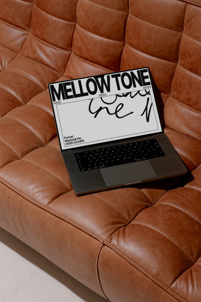 Laptop on brown leather couch displaying brush script font for digital asset mockup, perfect for graphic design presentations.