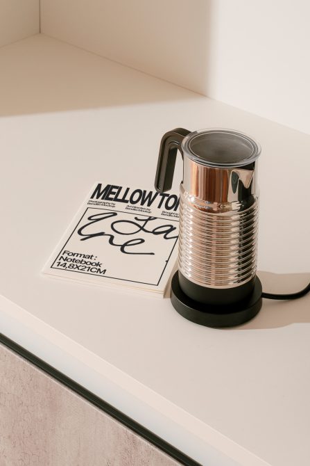 Elegant coffee maker on a minimal workspace with a designer's notebook, ideal for mockups, showcasing modern kitchenware design.