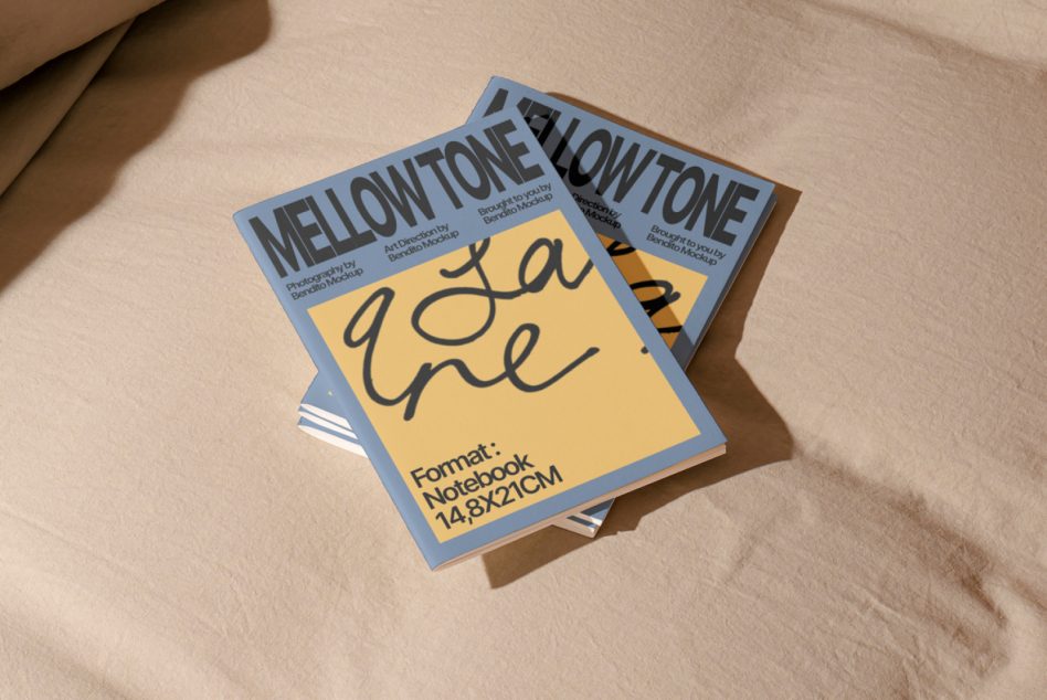 Stack of blue framed notebook mockups with yellow covers on neutral fabric